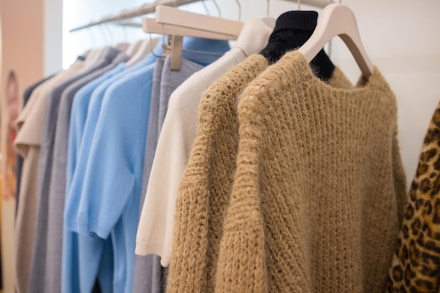 Pastel knit warm sweaters on white hangers.