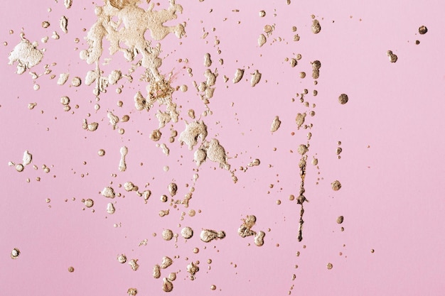 Pastel pink cardboard with gold potal drops and splashes. Creative background.