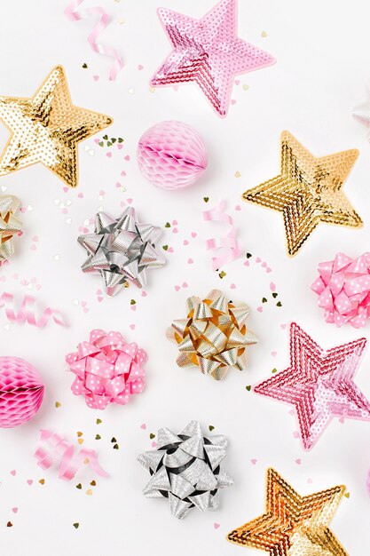 Foto coriandoli rosa pastello, fiocchi e decorazioni in carta. disposizione piana, vista dall'alto. composizione festiva per festa di compleanno, festa di capodanno/natale o tema del concetto di addio al nubilato. disposizione piatta, vista dall'alto