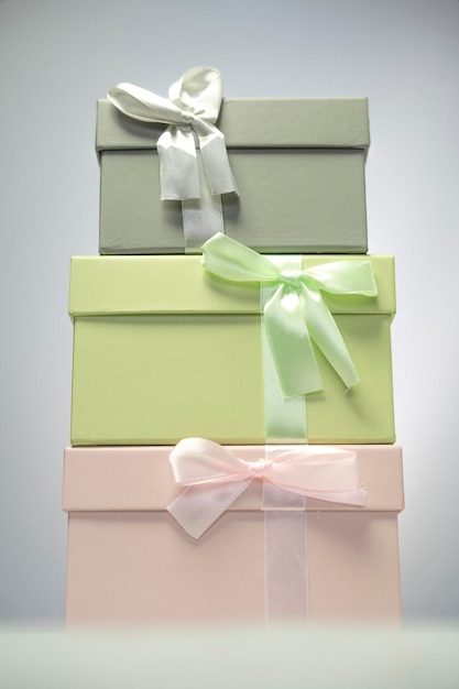 Foto scatole regalo rosa pastello e grigio in piedi l'una sopra l'altra con sfondo bianco