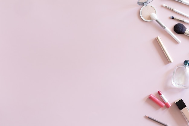 Pastel pink office table desk with beauty and make up accessories, cosmetics set, top view and flat lay. Home fashion women office workspace isolated on pink background.