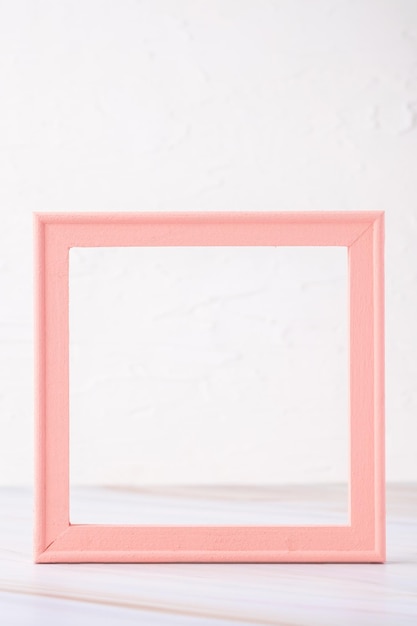 Pastel pink picture frame with olive leaf on marble table with concrete wall