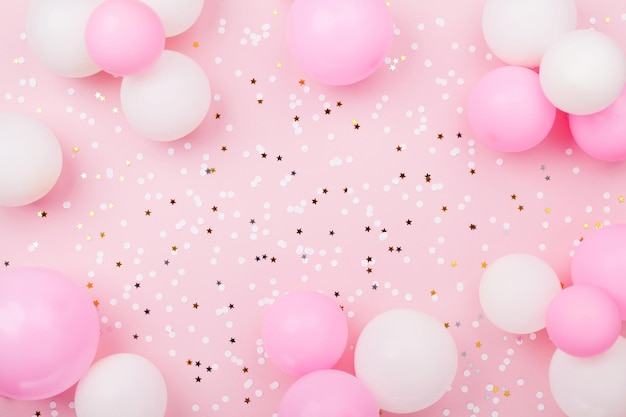 Pastel pink table with frame from balloons and confetti for birthday top view Flat lay composition