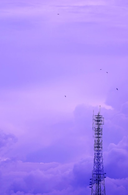 Пастельно-фиолетовая телекоммуникационная башня против облачного неба