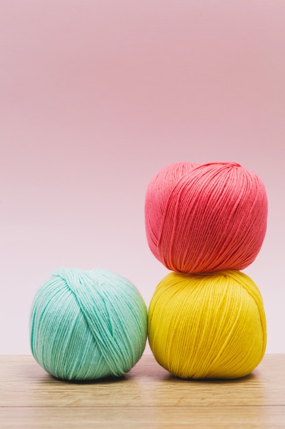 Pastel toned wool balls on wooden table and pink surface