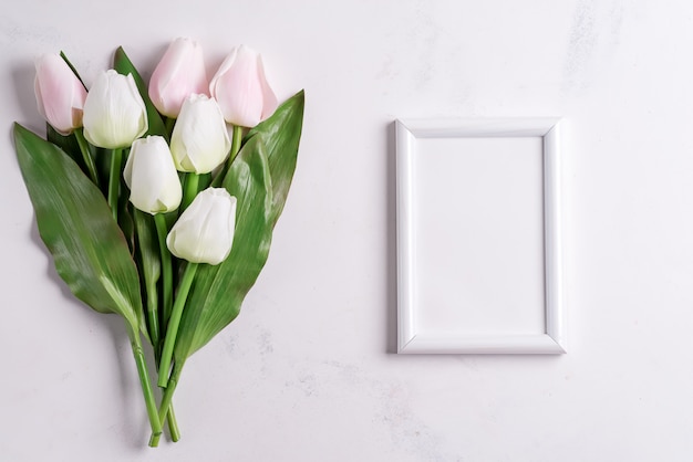 Tulipani pastelli con la cornice in bianco su fondo di marmo bianco, spazio della copia