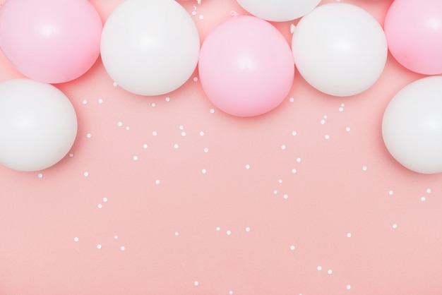 Pastelkleurige ballonnen en witte confetti op roze