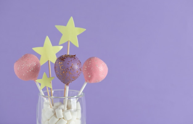 Pastelkleurige cake springt in een glas op een paarse muur. concept voor verjaardag, vakantie. horizontaal beeld. kopieer ruimte.