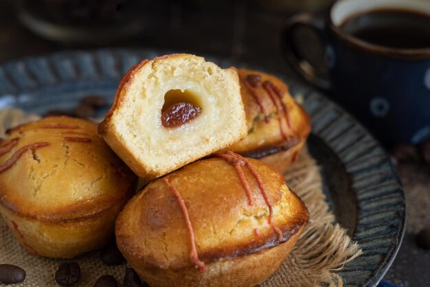 暗いテーブルのコーヒーカップの近くの深い青い皿のパスティチョット・レセセケーキ