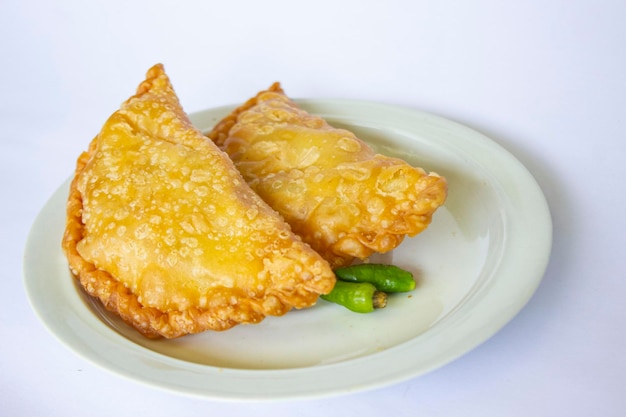 pastie cake or pastry cake or kue pastel served with green chili in little plate on wood background indonesian pastel cake