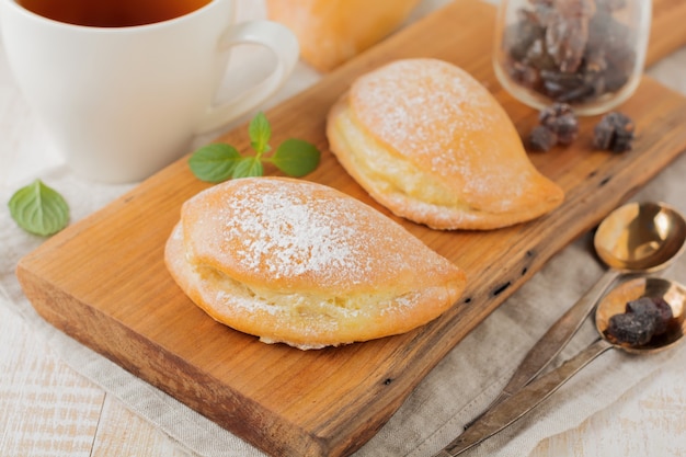 Photo pasties with cottage cheese and powdered sugar on a light wooden background traditional russian pastry sochnik