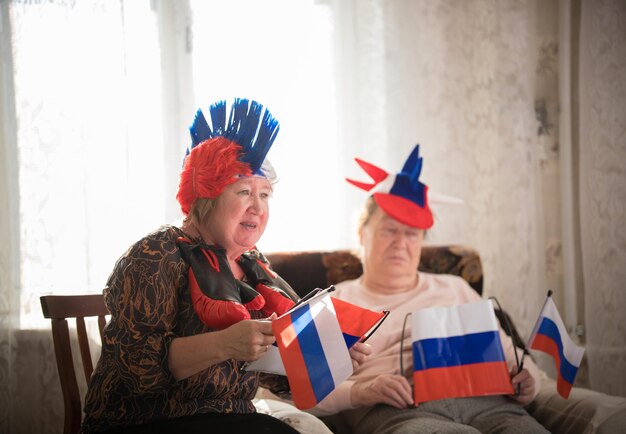 Pastimes an elderly women supports sport team sitting against tv on the backgrond of window