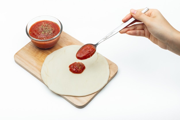 Foto incollare la salsa di pizza sull'impasto della pizza