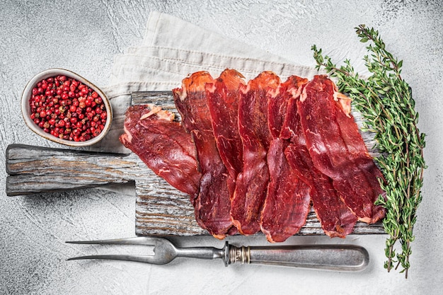 Pastirma turkish sliced pastrami dried beef meat with spices on\
wooden board white background top view