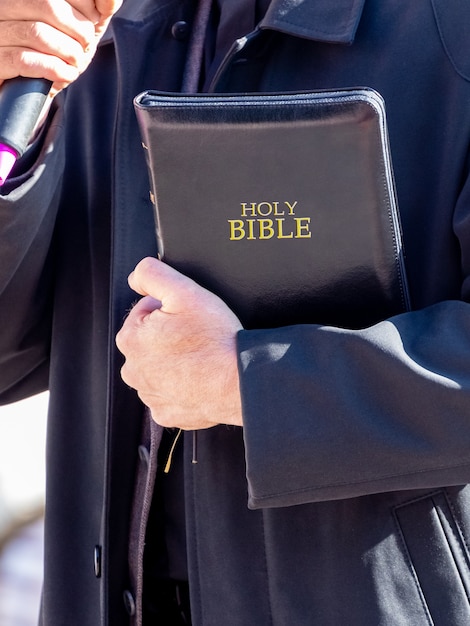 Pastor met een Bijbel in zijn hand tijdens een preek. De predikant houdt een toespraak