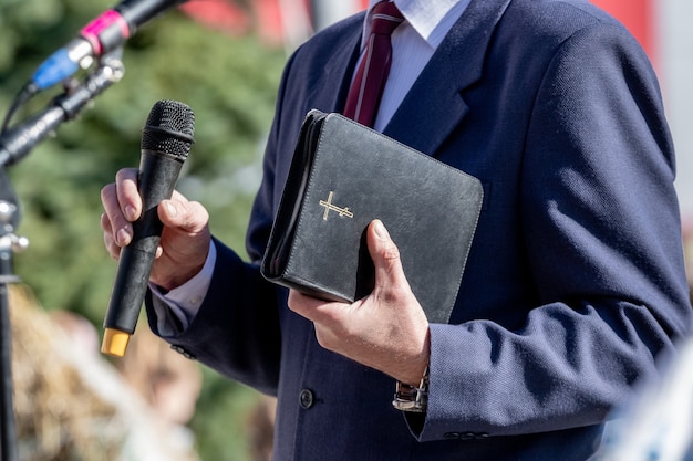 写真 説教中に聖書を手にした牧師。説教者はスピーチをします
