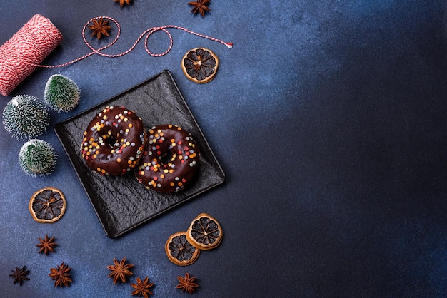 Pastries concept Donuts with chocolate glaze with sprinkles on a dark concrete table