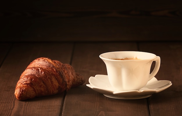 Pasticcini, croissant su un tavolo di legno marrone, con una tazza di caffè, colazione, nessun popolo, stile rustico, foto di alta qualità