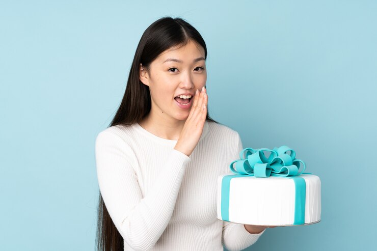 Photo 一位亞洲糕點<unk>師拿著一塊大蛋糕