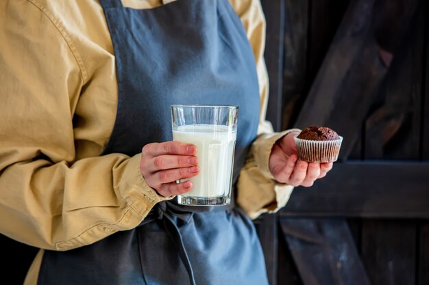 Pastry chef in apron holds chocolate cake and milk