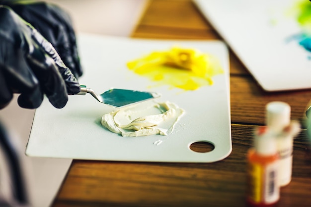 Foto il pasticcere in guanti di gomma neri mescola la panna colorata con la spatola per decorare la torta colorante alimentare per crema