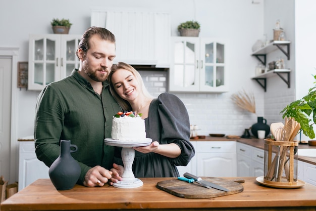 Pastry chef confectioner young caucasian woman with husband boyfriend man try taste of cake on kitchen table Cakes cupcakes and sweet dessert