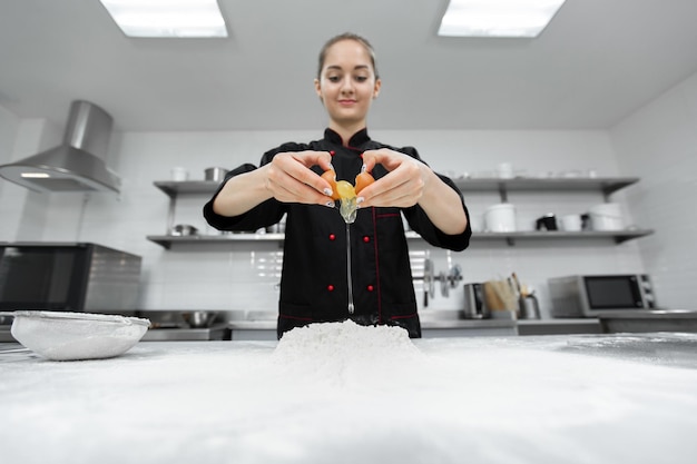 Pastry chef cracking an egg over white flour