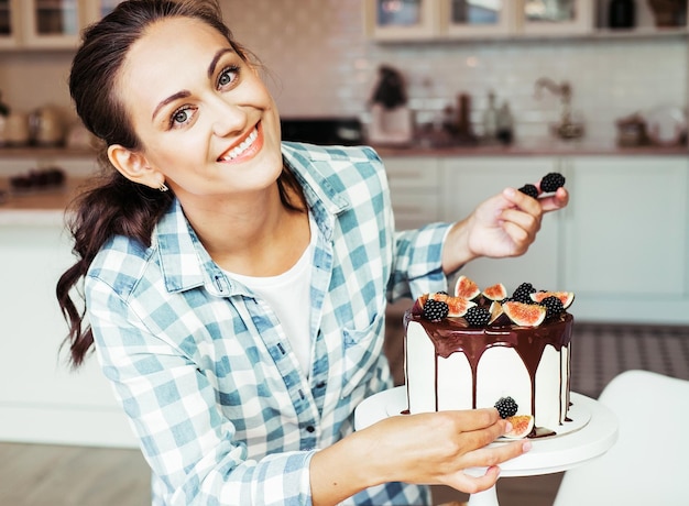 Il pasticcere decora la torta con frutti di bosco e fichi