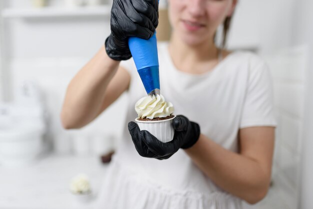 The pastry chef decorates the muffin with cream