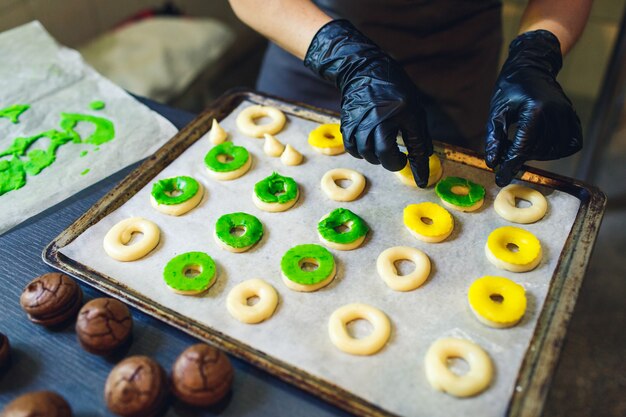생과자 요리사는 생 프로 페 테롤을 녹색과 노란색 쇼트 크러스트 페이스트리로 장식합니다.