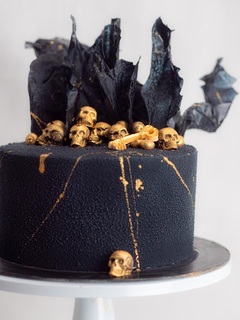 Photo pastry chef finishing horror black muertos birthday cake decorating with golden edible skulls and black rice paper sails