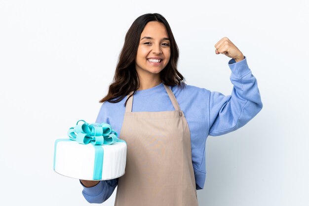 Pastry chef holding a big cake isolated doing strong gesture