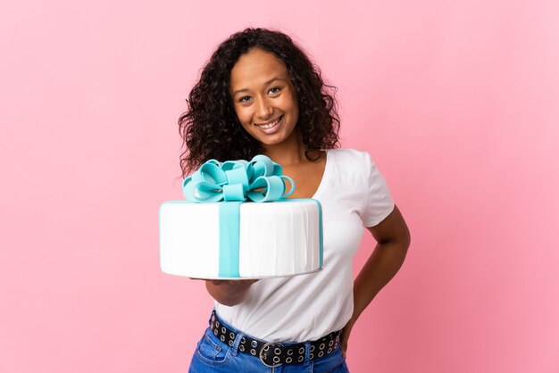 Pastry chef holding a big cake isolated on pink background with happy expression