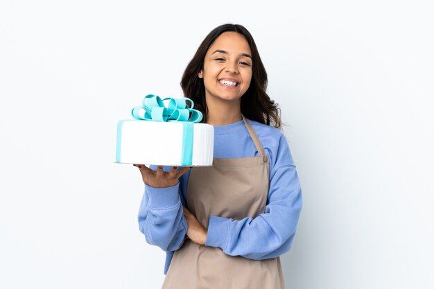 Pastry chef holding a big cake over isolated white laughing