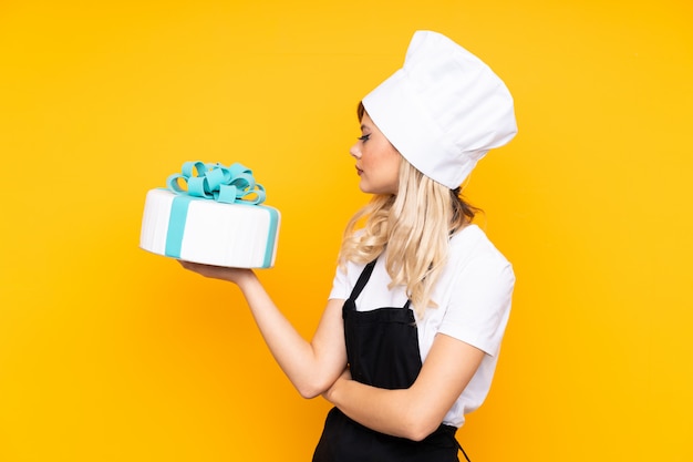 Pastry chef holding a big cake over isolated