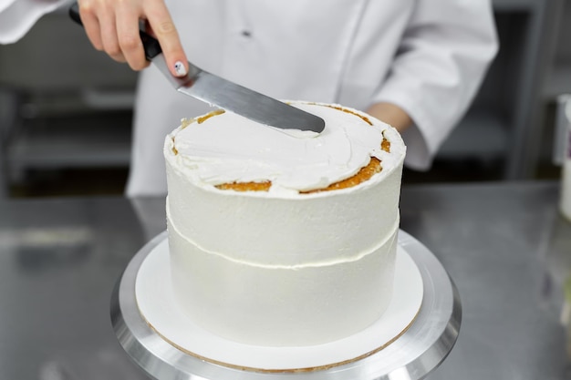 The pastry chef levels the cake with cream