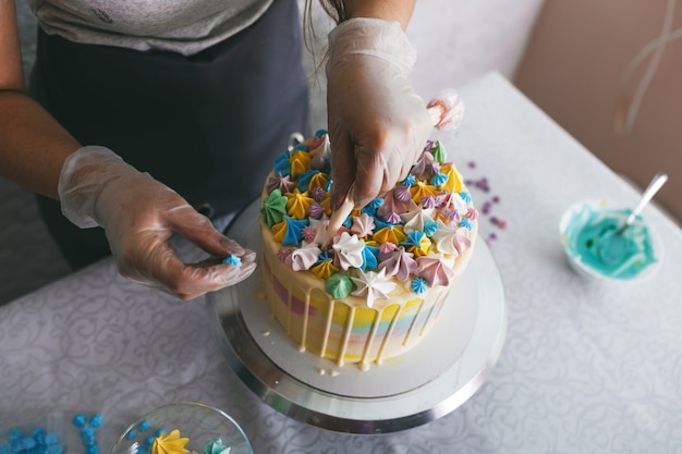 Una pasticcera fa una torta nuziale con le sue mani e applica decorazioni colorate sulle torte con la crema