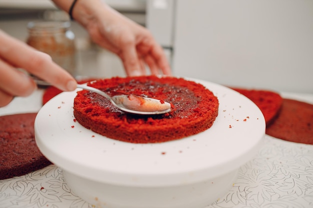 Pastry chef makes with jam delicious red velvet cake. Cooking and decorating dessert.