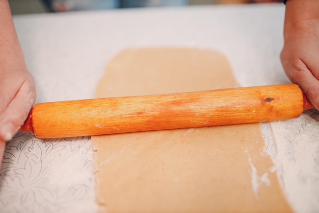 Pastry chef rolls out dough with rolling pin and makes delicious ginger cookies Cooking and decorating dessert