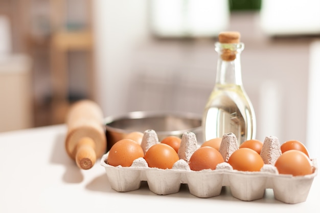 Pastry ingredients for homemade cakes and bread in empty kitchen. Modern dining room equipped with utensils ready for cooking with wheat flour in glass bowl and fresh eggs on table