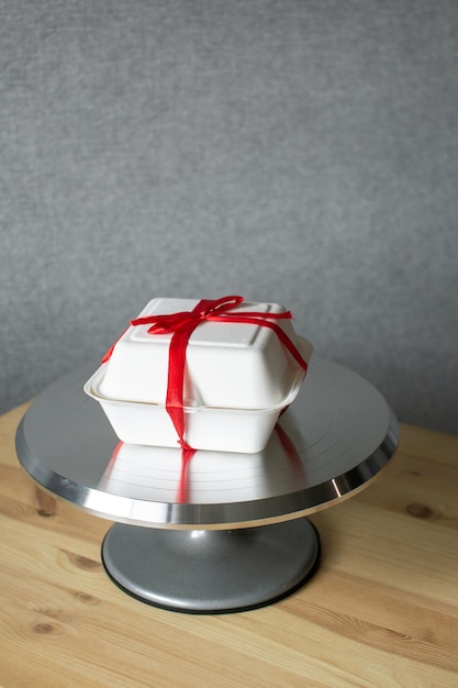Pastry metal turntable for cakes on wooden table with red ribbon cake bento packaging