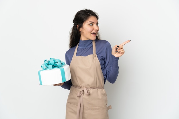 Pastry Russian chef holding a big cake isolated on white background intending to realizes the solution while lifting a finger up