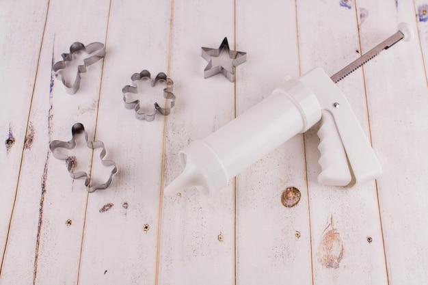 Pastry syringe with molds on wood background