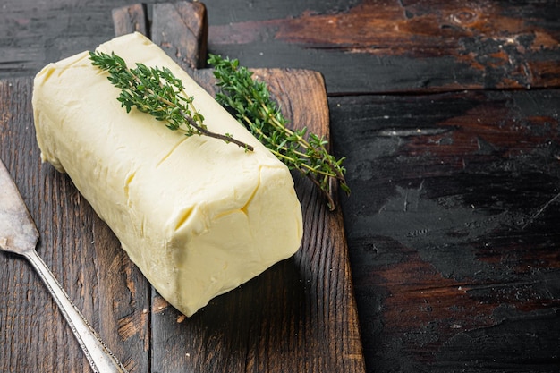 Pat of farm fresh butter on old dark wooden table background with copy space for text