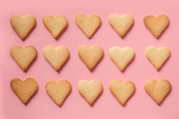 Patern of homemade heart shaped cookies on pink. Flat lay.