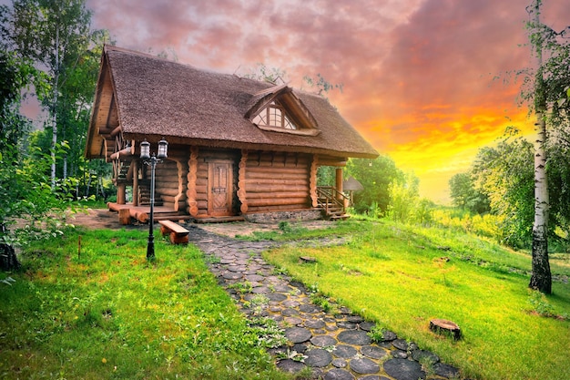 Photo path and wooden house in birch grove under dramatic sunset skies