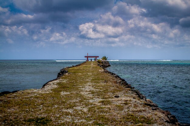 Pathway amidst river against cloudy sky at dusk