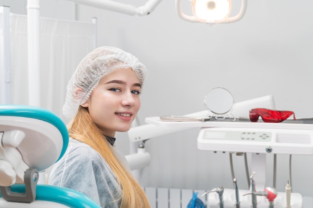 patient - a beautiful girl sits in a chair in the dentist office, turning back