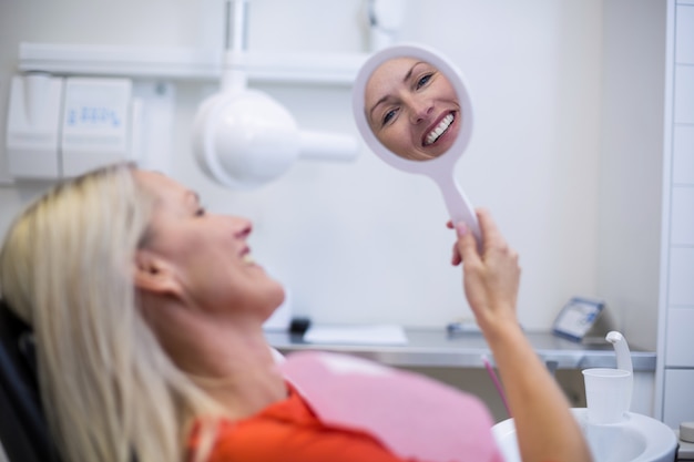 Foto paziente che controlla i suoi denti in specchio