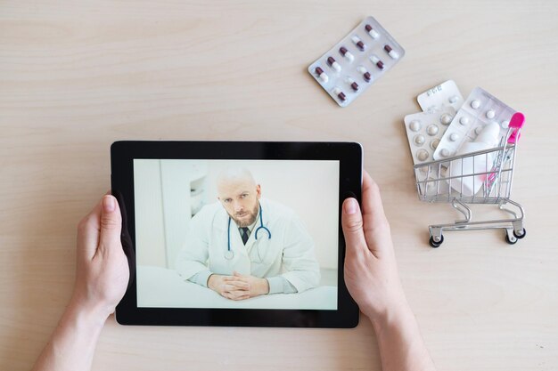 The patient communicates with a male therapist via video chat on a digital tablet Woman at online consultation with a doctor Online pharmacy concept Mini medicine trolley